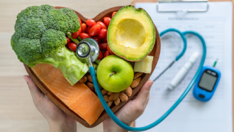 Frutas e legumes dentro de uma fruteira em forma de coração com um medidor de tensão ao lado.